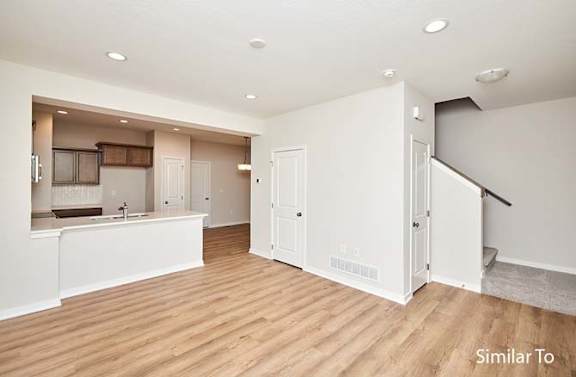 an empty living room and kitchen with a wooden floor at Two Rivers Home Rentals, West Des Moines, IA 50266