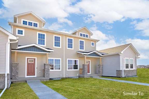 a beige house with a sidewalk in front of it at Two Rivers Home Rentals, West Des Moines, IA