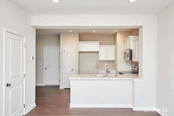 an empty kitchen with white cabinets and a sink at Two Rivers Home Rentals, West Des Moines