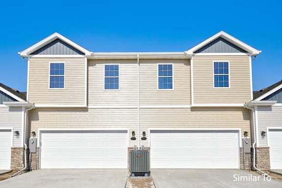 a tan house with two garage doors at Two Rivers Home Rentals, West Des Moines, Iowa