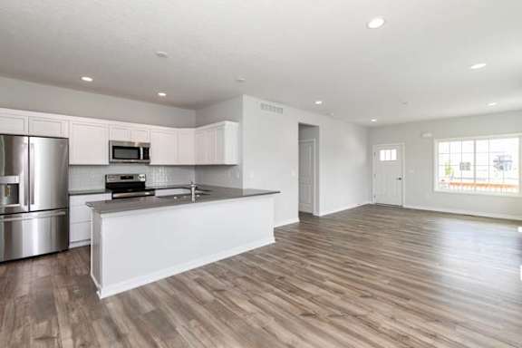 an empty kitchen with a refrigerator and a sink at Two Rivers Home Rentals, West Des Moines, IA 50266
