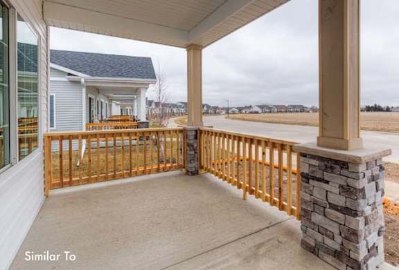 a large porch with a stone wall and a house at Two Rivers Home Rentals, West Des Moines