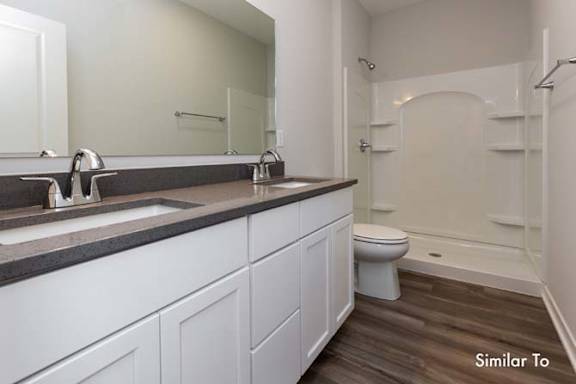 a bathroom with a sink and a toilet and a mirror at Two Rivers Home Rentals, West Des Moines, Iowa