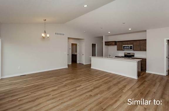 an empty living room and kitchen with wood flooring at Two Rivers Home Rentals, West Des Moines, 50266