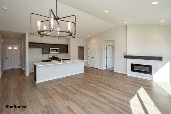 a living room with a kitchen and a chandelier at Two Rivers Home Rentals, West Des Moines, IA 50266