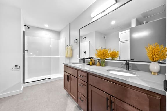 A bathroom with brown cabinets and a white counter top.at Plant 1 Lofts, Iowa