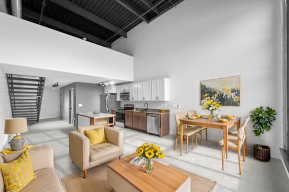 A modern living room with a dining area and a kitchen in the background.at Plant 1 Lofts, N. Newton, IA 50208