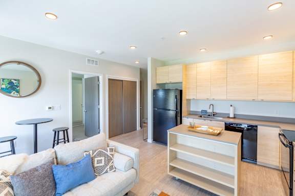 A modern kitchen with a black refrigerator and wooden cabinets.at Rowat Lofts, Des Moines Iowa
