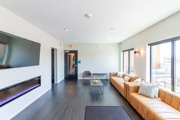 A modern living room with a long couch and a flat screen TV.at Rowat Lofts, Iowa, 50309