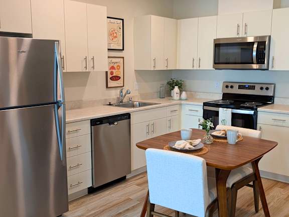 Kitchen with stainless steel appliances and dining table at Ovation at Paine Field