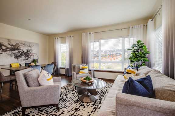 A living room with a grey couch, a coffee table, and a large painting on the wall.