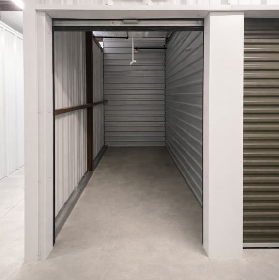 A storage unit with a closed grey shutter and a white door.