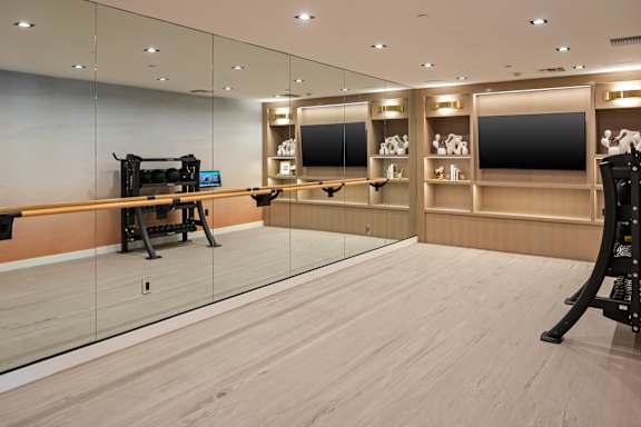 A gym with a mirrored wall and wooden floors.
