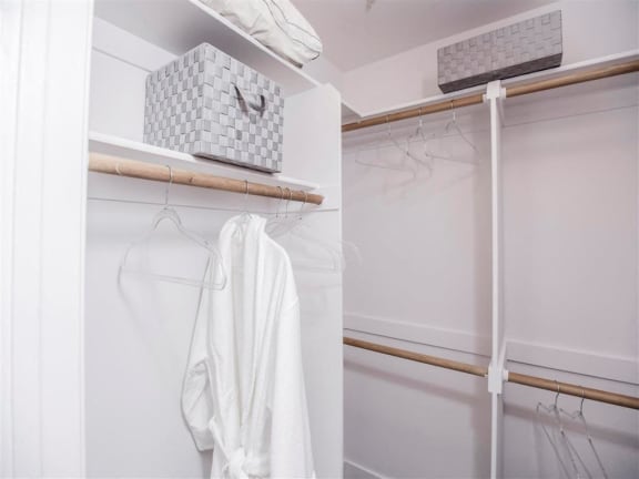 a white closet with white robes and a white towel on a rack