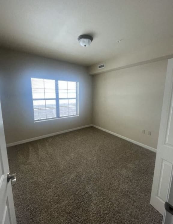 an empty room with a window and a carpet