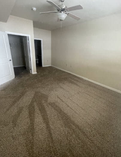 an empty living room with carpet and a ceiling fan
