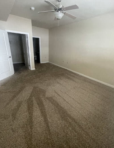 an empty living room with carpet and a ceiling fan