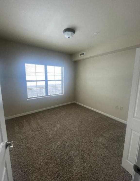 an empty room with a window and a carpet