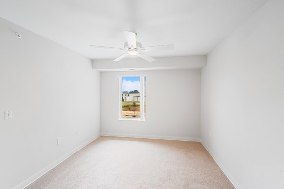 an empty room with a ceiling fan and a window