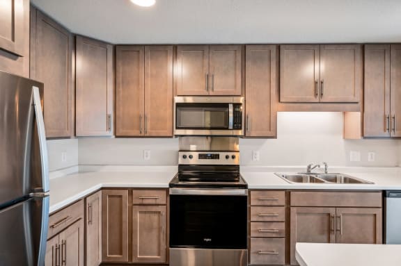 an empty kitchen with wooden cabinets and stainless steel appliances