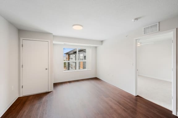 an empty living room with wood flooring and a window
