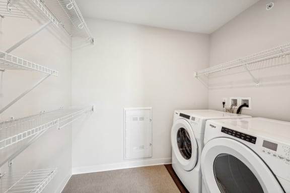 a washer and dryer in a laundry room with white walls and white shelves