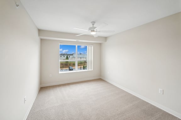 an empty room with a window and a ceiling fan