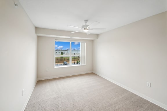 an empty room with a window and a ceiling fan