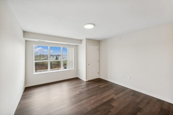 an empty living room with wood floors and a window