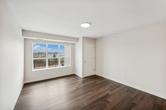 an empty living room with wood floors and a window
