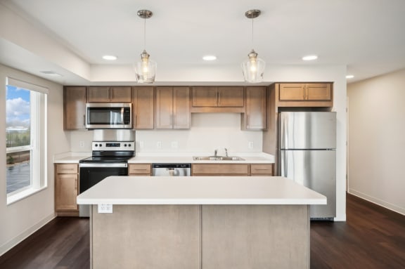 an empty kitchen with a white island and stainless steel appliances