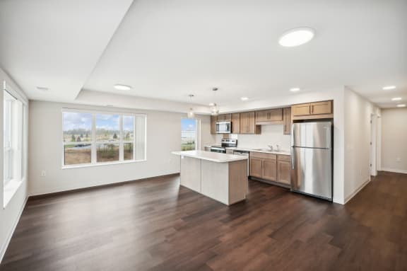 a large kitchen with a large window and a stainless steel refrigerator