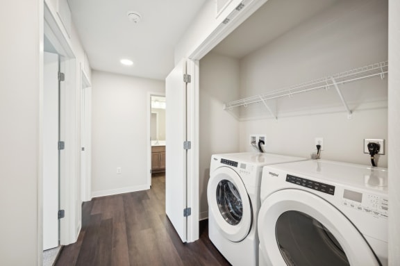 a washer and dryer in a laundry room with white walls and wood floors