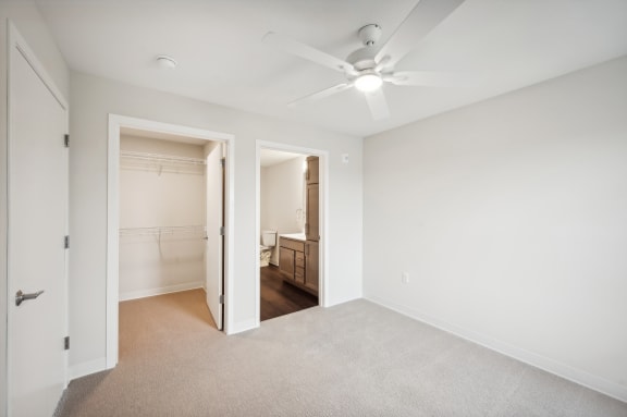 an empty bedroom with a ceiling fan and a closet