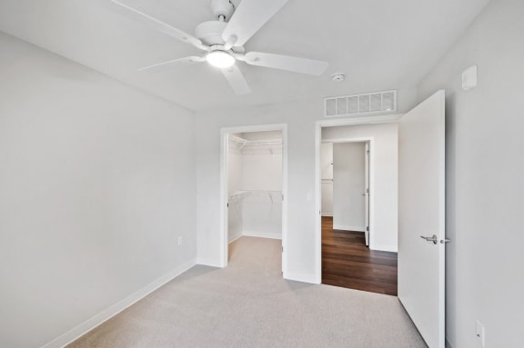 a bedroom with white walls and a ceiling fan