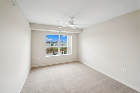 an empty room with a window and a ceiling fan