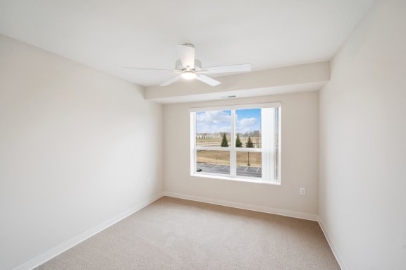 an empty room with a window and a ceiling fan