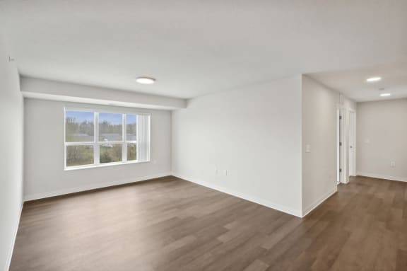 an empty living room with white walls and a window