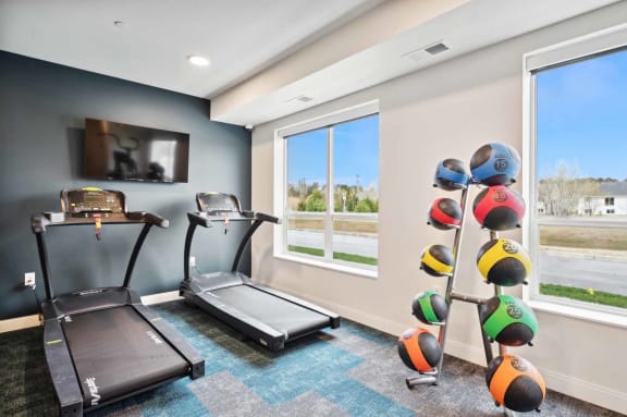 a gym with two treadmills and a tv on the wall