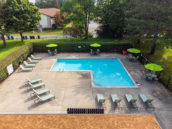 a swimming pool with chairs and umbrellas around it