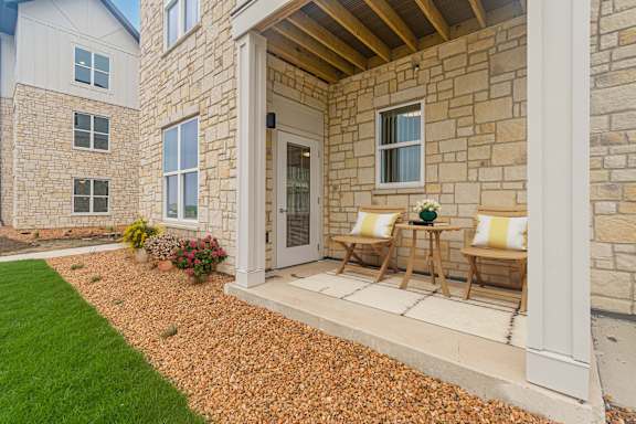 A house with a white door and two chairs on the porch.