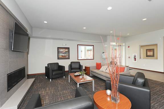 A living room with a grey couch, a black chair, a brown coffee table, and a television.