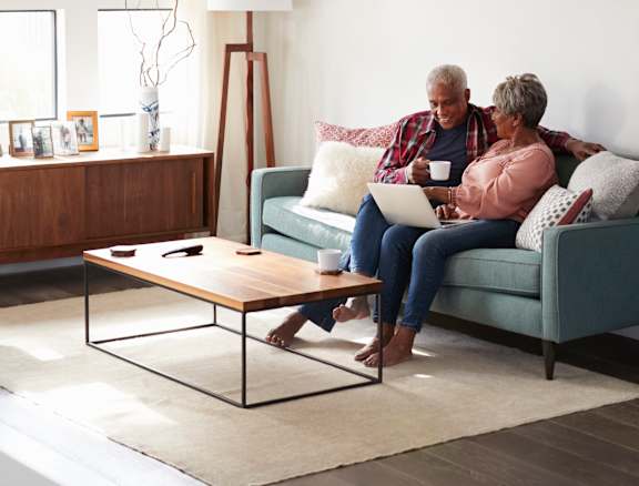Two people sitting on a couch with a laptop.