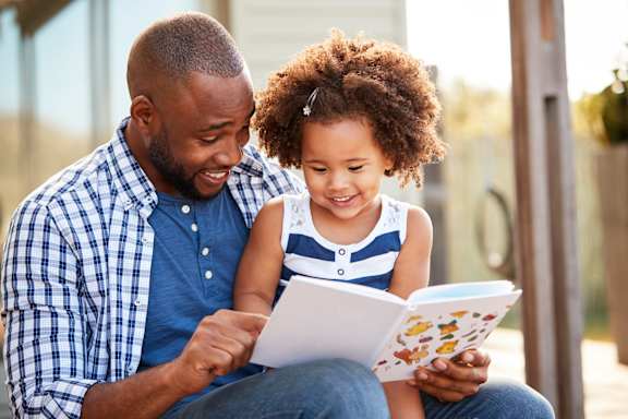 A man and a child are reading a book together.