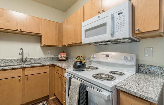 a kitchen with white appliances and granite counter tops and wooden cabinets