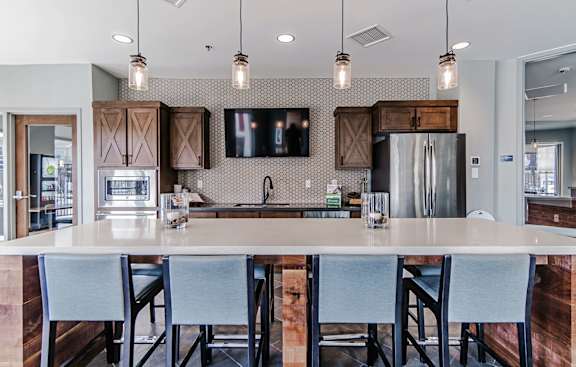 A kitchen with a white countertop and grey chairs.