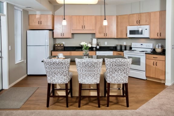 a kitchen with white appliances and wooden cabinets at The Grainwood Senior Apartments, Prior Lake, MN 55372