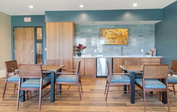 a dining area with tables and chairs and a kitchen in the background  at Legacy Commons at Signal Hills 55+ Apartments, West St. Paul, MN, 55118