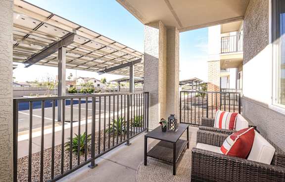 A balcony with a table and chairs is covered by a roof.