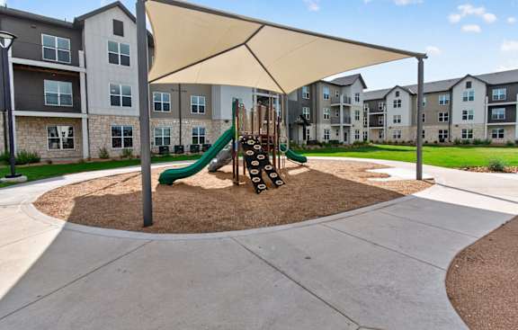 A playground with a green slide and a brown sandbox.